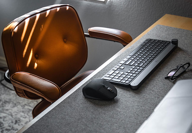 Tastatur-Sonderzeichen. Bild zeigen einen Schreibtisch mit Tastatur und Maus sowie einem Schreibtischstuhl aus braunem Leder. Bild: Unsplash/Michael Soledad.